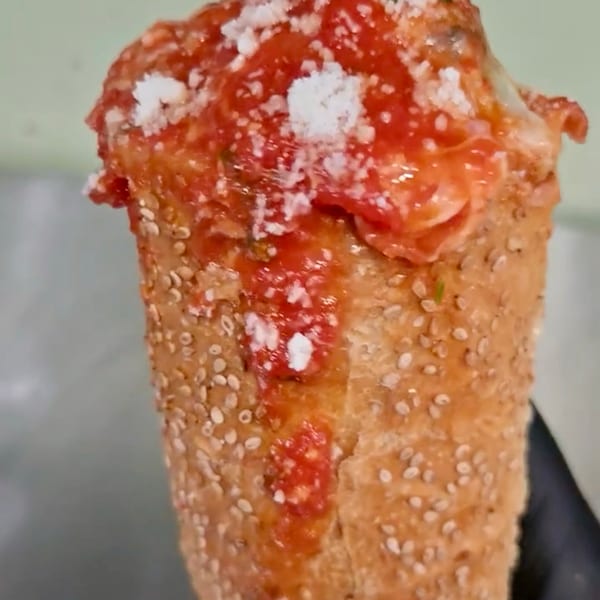 A bread cone filled with red sauce, melted cheese, and sprinkled with parmesan.